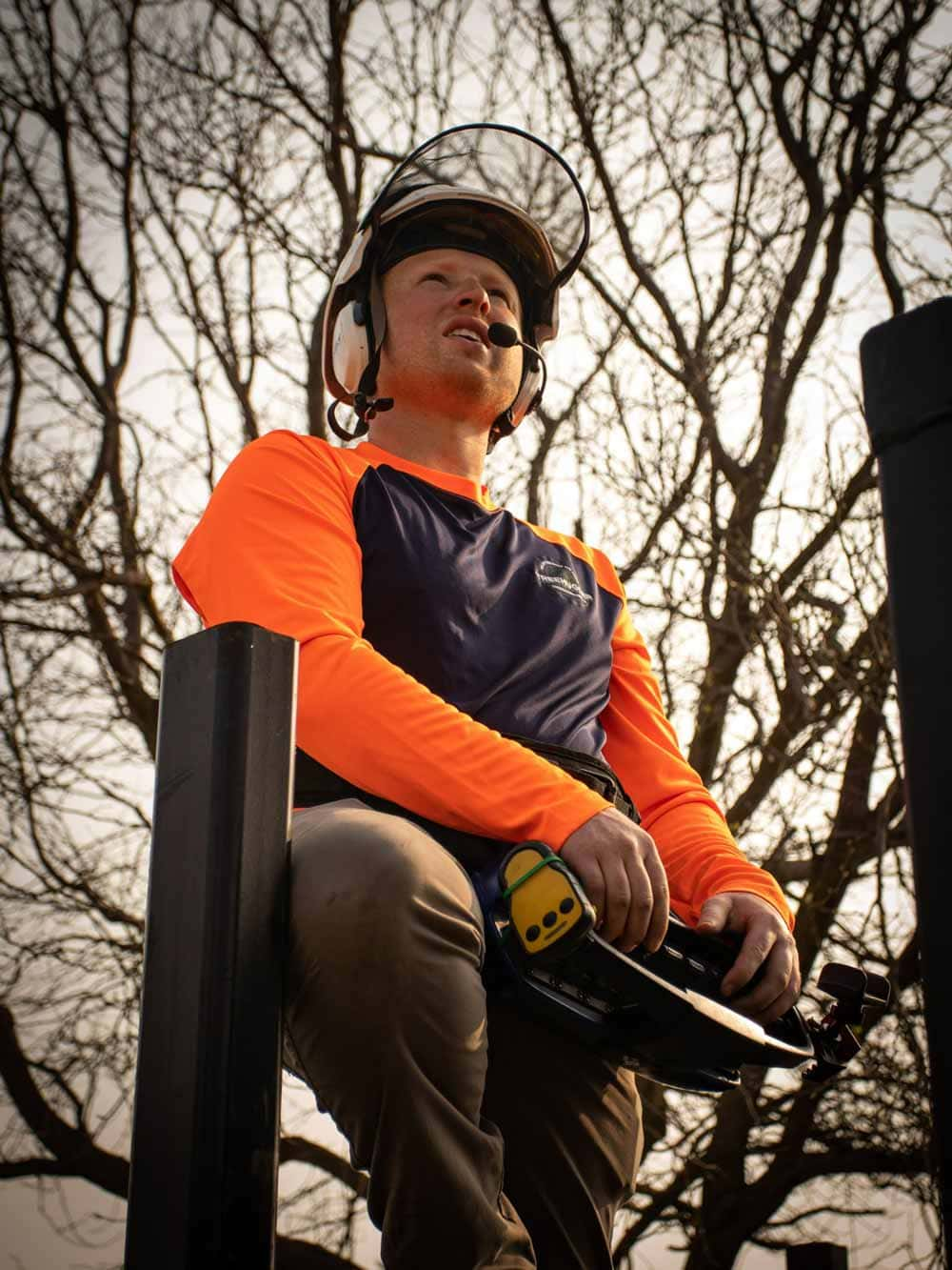 Sean Deakins, ISA Certified Arborist in a tree stand holding a tree saw. 